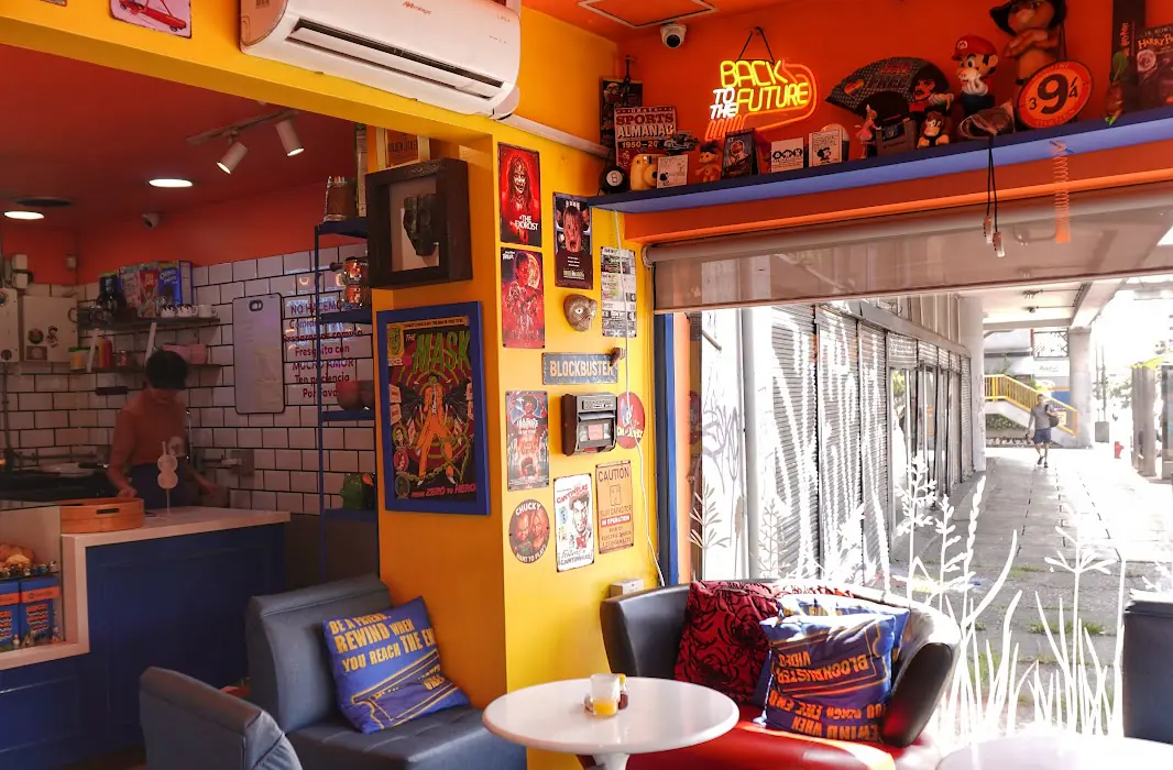 Interior de 88 Café & Deli: paredes naranja y amarillo, sillones y cuadros retro
