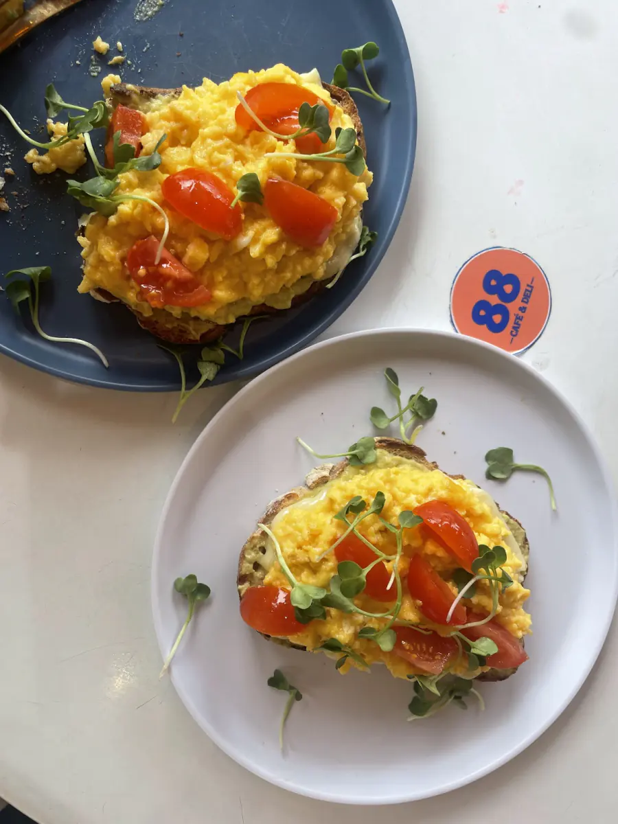 Huevos revueltos con tomate y germinados sobre tostadas