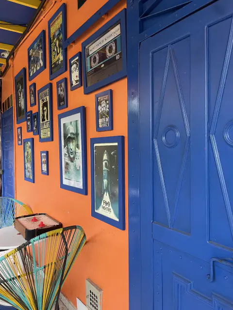 Pared naranja con cuadros y puerta azul