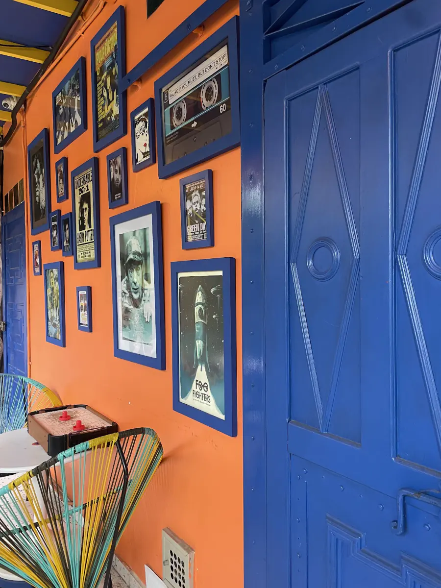 Pared naranja con cuadros retro junto a la puerta azul de 88 Café & Deli